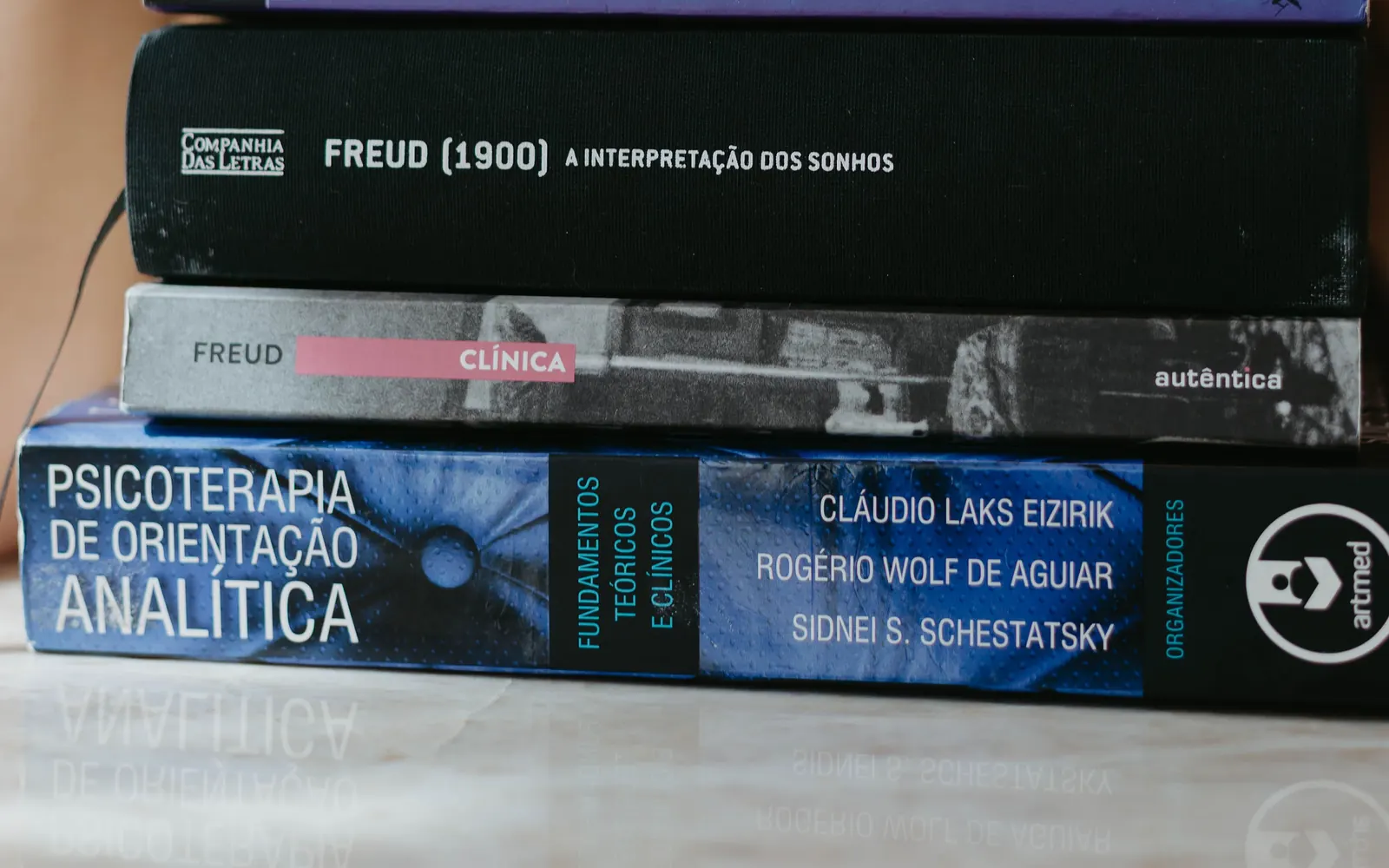 Livros de psicanálise empilhados sobre a mesa, entre eles obras de Freud