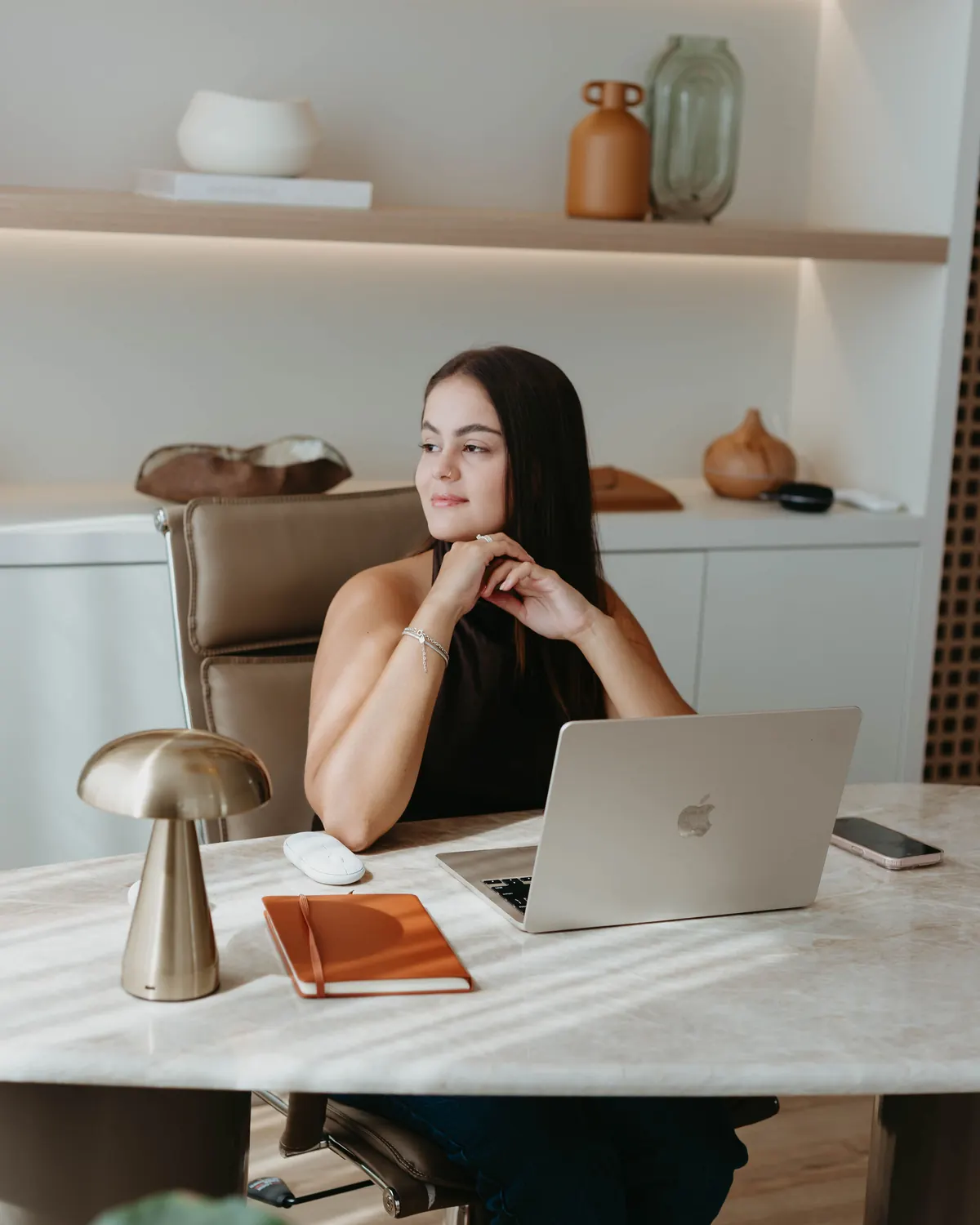 Mikaella Nunes de Souza em sua mesa de trabalho, com notebook e caderno